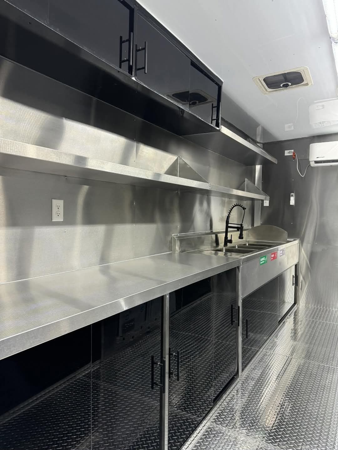 Vista 2 del interior del food truck con equipo de cocina y superficies de acero inoxidable.