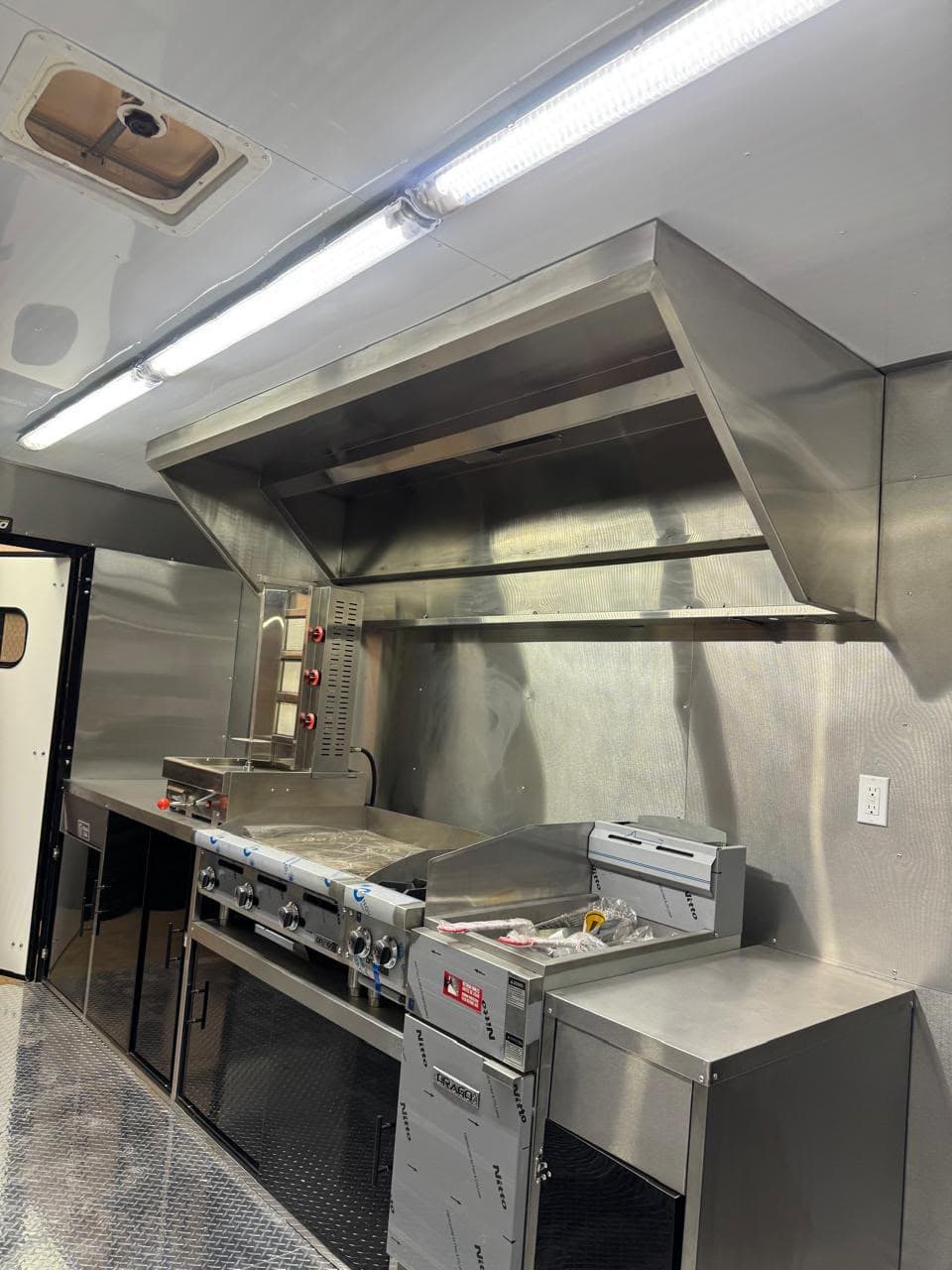 Vista 6 del interior del food truck con equipo de cocina y superficies de acero inoxidable.